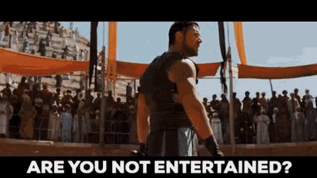 Animated gif: Russel Crow in Gladiator, after winning his first fight, arms wide holding a sword and addressing the crowd: 'are you not entertained?'